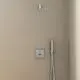 Shower area mit einer oberen Regenbrause und einem Handbrausehalter. Die Armaturen sind aus verchromtem Metall und stammen von Ideal Standard. Wände in neutralem Farbton.